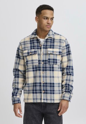 Blue and cream plaid flannel shirt with button-up front, two chest pockets, and long sleeves, featuring wooden buttons and a collar.