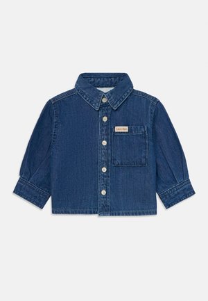Długa koszula z ciemnoniebieskiego denimu z zapięciem na guziki i kieszenią na klatce piersiowej z małą metką Calvin Klein.