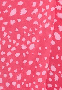 Růžová látka s výrazným, texturovaným vzorem nepravidelných světle růžových skvrn a fleků, s mírně chlupatým povrchem.