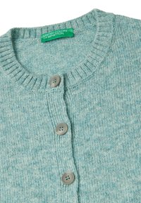 Jasnoniebieski sweter z dzianiny z okrągłym dekoltem, prążkowaną fakturą i trzema szarymi guzikami wzdłuż zapięcia z przodu.