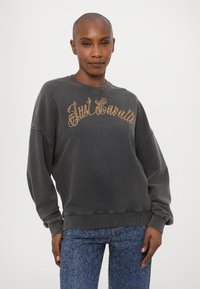 Γκρι φούτερ με την ένδειξη "Just Casuals" από χρυσές πόντους, με στρογγυλή λαιμόκοψη και άνετη εφαρμογή. Ο υφασμάτινος σχεδιασμός και οι ριμπ μανσέτες ολοκληρώνουν την εμφάνιση.