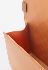 Borsa in plastica morbida arancione con finitura testurizzata. L'interno presenta una tasca in rete e bordi lisci, con dettagli in metallo.