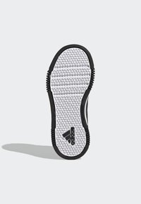 Sola di sneaker bianca e nera con un motivo esagonale, caratterizzata da un logo Adidas prominente e lati in gomma nera testurizzata per una migliore aderenza.