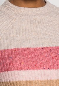Gebreid trui met een ribbelstructuur, met horizontale strepen in beige, lichtroze en donkerroze, met kleurrijke spikkels doorheen.