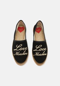Juodos espadrilės su smėlio spalvos siuvinėtu „Love Moschino“ tekstu. Turėti šiaudų juto pado, elastingus šoninius panelius ir raudoną širdies logotipą viduje.