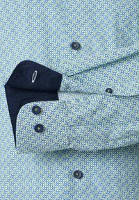 Groene en blauwe gestreepte overhemden met donkerblauwe knopen en contrasterende marineblauwe manchetlijnen, met ingewikkelde ronde ontwerpen.