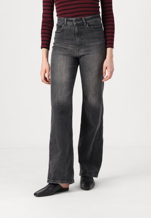 High-waisted black denim jeans with a straight leg, slightly faded texture. Paired with black slip-on shoes. The top is burgundy with stripes.