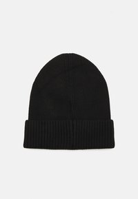 Gorro de punto negro hecho de un material texturizado que presenta un dobladillo doblado y una corona cónica, proporcionando un ajuste ceñido en la cabeza.