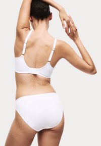 Vitt bikinitset med en mjuk, sömlös design, justerbara remmar och ett enkelt elastiskt band. Slät yta och minimala detaljer.
