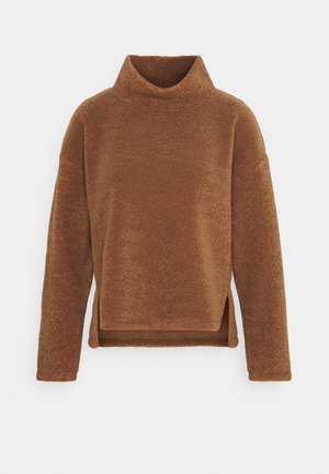 Brązowy polarowy sweter z długim rękawem, wysokim kołnierzem i bocznymi rozcięciami, ukazujący miękką, teksturowaną tkaninę na jednolitym tle.
