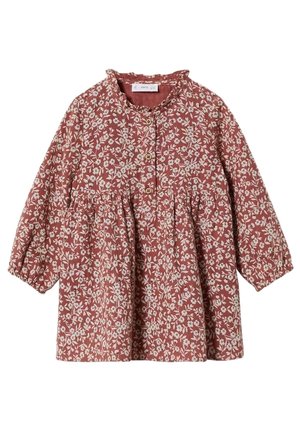 Vestido de niña de manga larga con fondo óxido y estampado floral blanco, botones de madera en la parte delantera y detalle en la cintura fruncida.