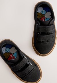 Melnas auduma kurpes ar divām Velcro siksnām, gumijas zolēm un krāsainiem karikatūru zolēm ar abstraktiem rakstiem. Gluda tekstūra ar apaļu formu.