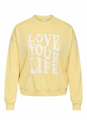 Gelber Pullover mit weißen Blockbuchstaben mit der Aufschrift „LOVE YOUR LIFE“ und einem kleinen Herz über dem Wort „LOVE“.