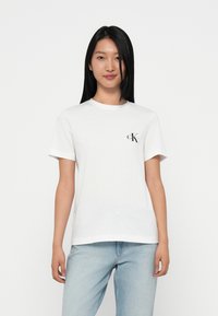Λευκό βαμβακερό T-shirt με κοντά μανίκια και στρογγυλή λαιμόκοψη. Διαθέτει μαύρο λογότυπο 'CK' στο αριστερό στήθος. Συνδυάζεται με ανοιχτόχρωμο τζιν μπλε.