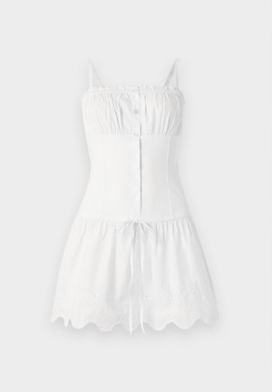 Balts kokvilnas kleita ar plānām siksnām, pogu priekšpusi, pieguļošu augšdaļu un izplestu svārku. Iezīmē izšūtu viļņotu apakšmalu un auklas vidukli.