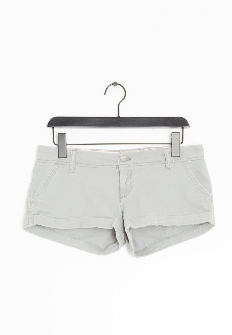 Shorts décontractés en coton gris clair avec bouton et fermeture éclair à l'avant, passants de ceinture et deux poches avant, suspendus à un cintre noir.