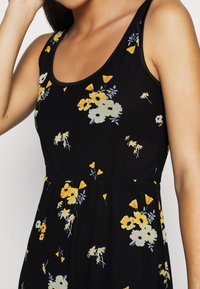 Vestido floral negro con escote redondeado, adornado con flores amarillas y blancas, y delicados acentos verdes, fabricado con un tejido suave y ligero.