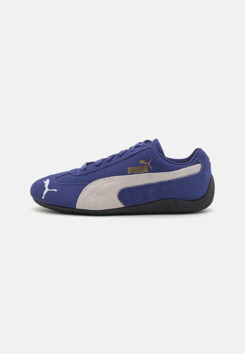 Lilla semsket sneakers med en beige sidelist, svart gummisåle og gulllogo detaljer. Har snøredesign og rund tå.