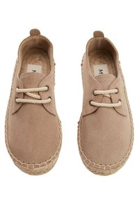 Suede beige shoes with round toe, two fabric laces, and woven jute sole. Features stitched detailing around the edge.