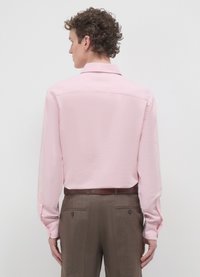 Hellrosa langärmliges Hemd mit glatter Textur, Standardkragen und geknöpften Manschetten, kombiniert mit braunen Hosen mit dezentem Muster.