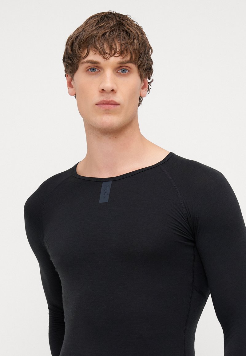 Black long-sleeve fitted shirt with a round neckline, made of smooth fabric, featuring a small label on the chest and raglan sleeves.