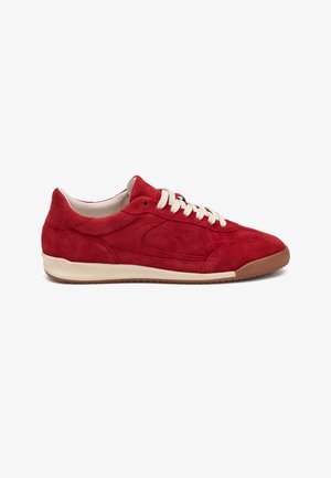 Zapatilla deportiva baja de ante rojo con cordones blancos, suela beige y puntera de goma marrón, vista desde el lateral exterior sobre un fondo blanco.
