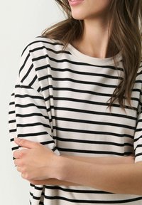 T-shirt à manches courtes rayé en mélange de coton doux, présentant des rayures horizontales noires et blanches, un col rond et une coupe décontractée.