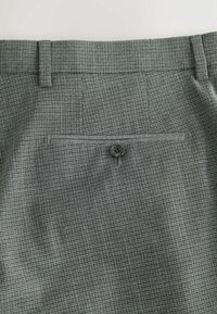 Sivé vzorované nohavice s hladkou textúrou, na zadnom vrecku je jeden čierny gombík. Prispôsobený strih.