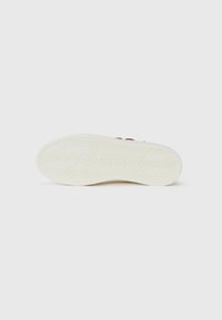 Valkoinen kumikenkäsole, jossa on herringbone-kuvio ja kohokuvioitu brändinimi. Siisti muotoilu, jossa on sileä ja kestävä pinta.