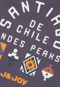 Paarse stof met witte tekst "Santiago de Chile Andes Peaks," versierd met kleurrijke geometrische vormen in oranje, zwart en wit. Merknnaam J&JOY.