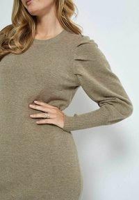 Knit sweater in light brown with puffed sleeves and ribbed cuffs. Soft texture, round neckline, and fitted bodice design.