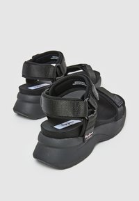 Sandalias de plataforma negras con correas de nylon ajustables, suela acolchada y una base de goma suave con acentos de logo.