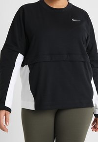 Sweatshirt à manches longues noir et blanc avec un col rond et un design superposé. Présente un petit logo Nike sur le devant et des manches unies.