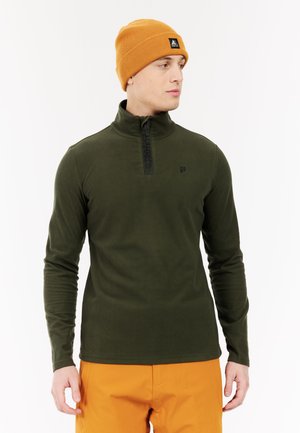 Olijfgroene fleece pullover met een hoge kraag en kwart-rits. Draag het met een oranje beanie met een zwart logo patch en een textuurstof.