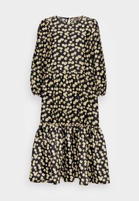 Schwarzes Kleid mit langen Ärmeln, an der Taille gerafft, mit einem gestuften Saum. Gelbes Blumenmuster durchgehend. Schlüsselaugen-Detail am Nacken.