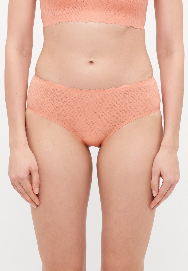 Set di lingerie color pesca con un design testurizzato, caratterizzato da bordi ondulati sul reggiseno e sui briefs a vita alta.