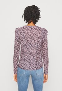 Langärmlige Bluse mit Rüschenschultern, Blumenmuster in Lila, Pink und Weiß; leichtes Material; glatte Textur; taillierte Form.