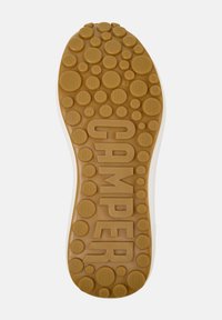 Gummisko med sulor i beige med cirkulära mönster och strukturerade detaljer, med "CAMPER" präglat i fet stil. Storlek 42 synlig.