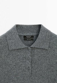 Šedý kašmírový polo svetr s klasickým límcem, řadou knoflíků a měkkou, texturovanou látkou. Na štítku značky je napsáno "Massimo Dutti."
