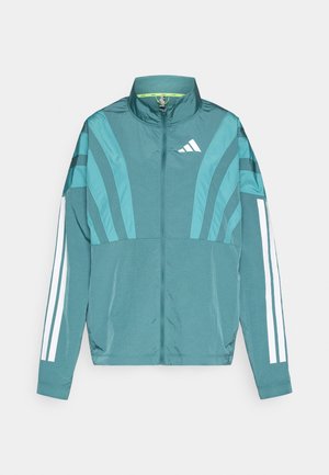 Veste de sport teal avec fermeture éclair sur le devant, col montant, trois bandes blanches sur les manches et des détails de design superposés. Tissu léger.