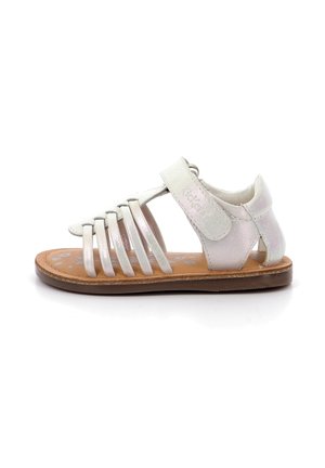 Sandalias de cuero blancas con múltiples correas verticales, cierre con hebilla y suela texturizada. Acabado ligeramente reflectante con una parte inferior marrón natural.