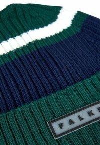 Berretto lavorato a maglia in verde scuro, blu navy e bianco con una trama a coste. Presenta un'etichetta rettangolare con il marchio e la scritta "FALK."