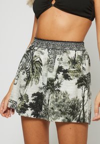 Falda con estampado floral en gris claro con tonos verdes y negros, que presenta una cinturilla elástica y un diseño fluido. El material parece ligero.