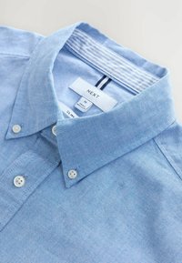 Jasnoniebieska koszula slim-fit z teksturowanej tkaniny, z kołnierzykiem zapinanym na guziki, dwoma guzikami na kołnierzyku oraz paskiem wewnętrznym w paski.