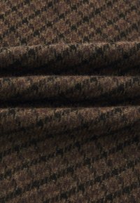 Țesătură din lână cu un model houndstooth, având forme maro închis pe un fundal maro deschis, cu o suprafață moale și texturată.