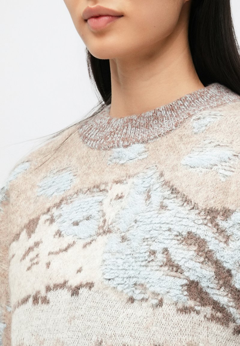 Maglione girocollo con un mix di trame beige e azzurro pallido, caratterizzato da una lavorazione morbida e soffice e da sottili motivi astratti.