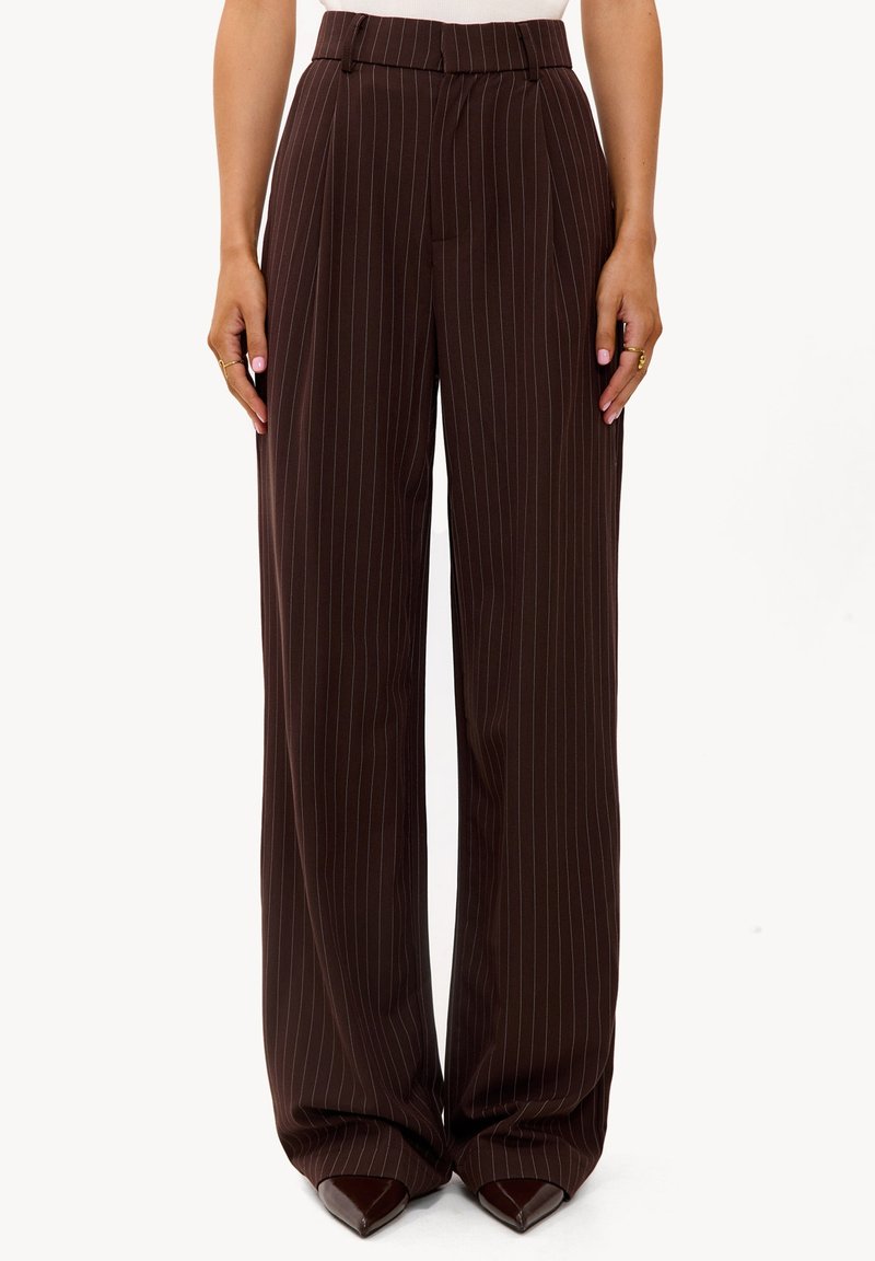 Pantalones de pierna ancha a rayas marrones con textura suave, cintura alta y calzado puntiagudo de color marrón oscuro. Corte entallado para un aspecto pulido.