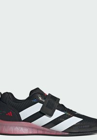 Sort sportsko med tre hvide streg, tekstureret overdel, Velcro-rem og gennemskinnelig pink sål. Funktioner med reflekterende accenter.