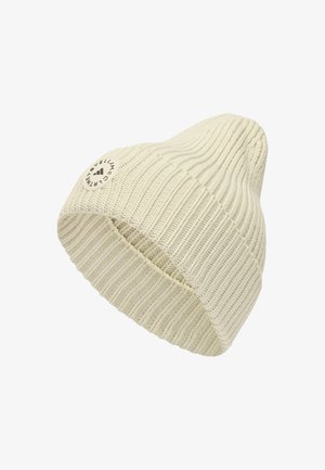 Gorro de malha creme com textura canelada, apresentando um emblema em forma de círculo cosido de lado. Tecido macio, design afunilado.