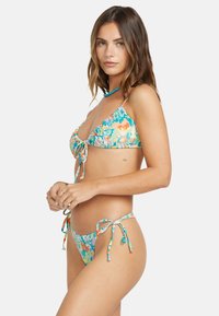 Bikini floreale realizzato in tessuto elastico. Presenta un design colorato con lacci sia sopra che sotto, mostrando un vivace motivo di fiori.